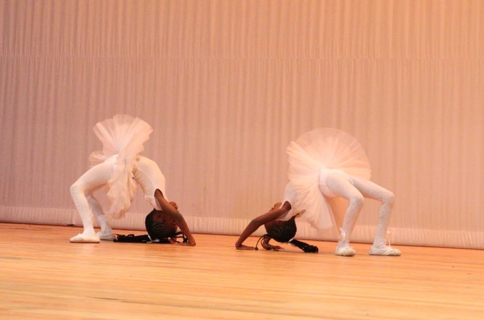 Two ballet dancers in white tutus performing on stage